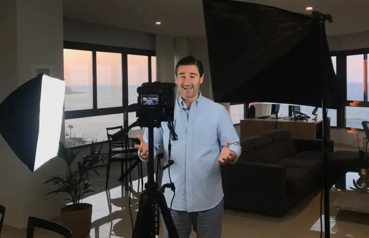 Man standing in front of camera and lights in a home studio setup, demonstrating how to start a video podcast.