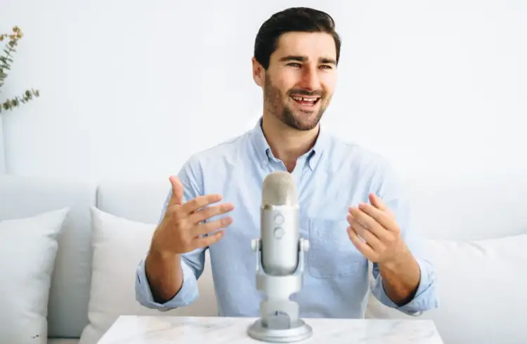 Liam Austin speaking while recording a podcast using a Blue Yeti microphone on a marble table