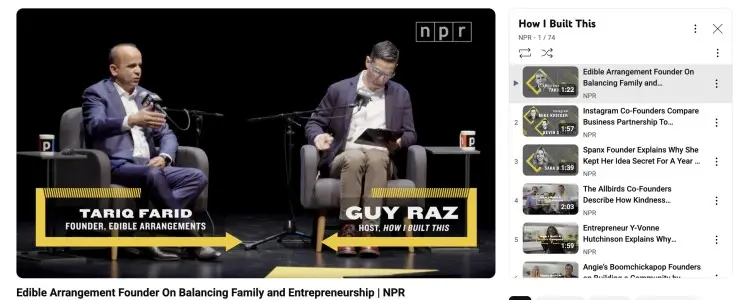 Interview setup from the How I Built This show with Guy Raz and Tariq Farid on stage, shown as a youtube video discussing entrepreneurship and business stories.