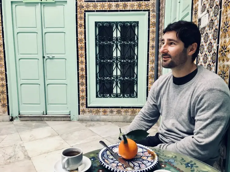 Man sitting at a café in a relaxed setting, demonstrating trustworthiness through authenticity and approachability