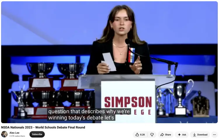 Student speaking onstage during a national debate competition to develop public speaking skills