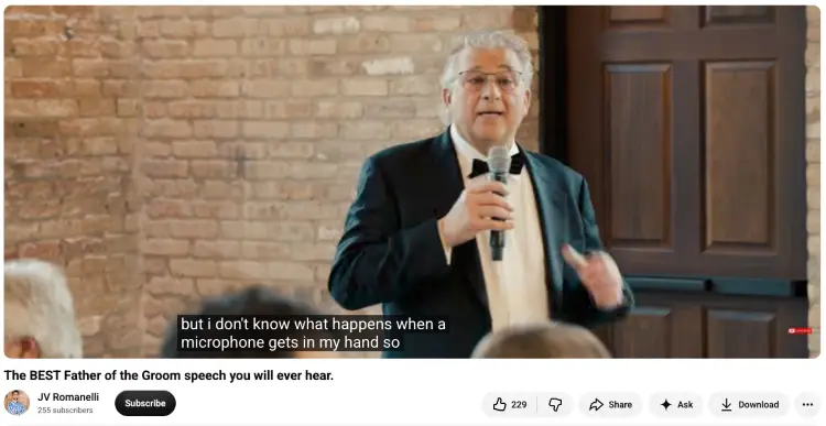 Father of the groom delivers a toast at a wedding while holding a microphone and speaking to seated guests.