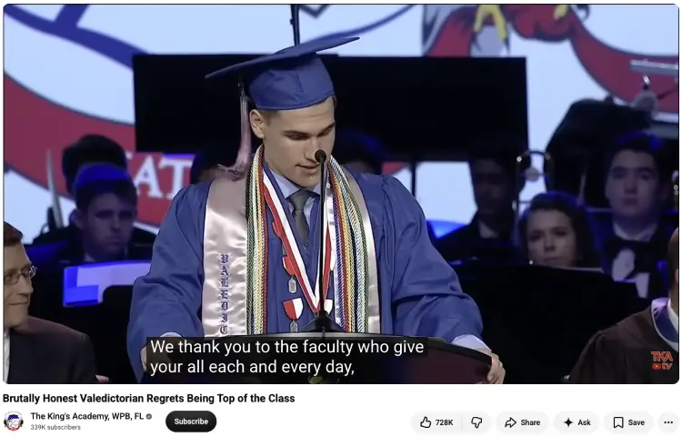 Male graduate in a blue cap and gown delivering a memorable valedictorian speech at a podium during a high school graduation ceremony.