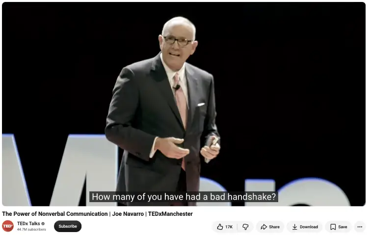 Joe Navarro presenting a TEDxManchester talk demonstrating non-verbal communication skills through body language, gestures, and social interactions.