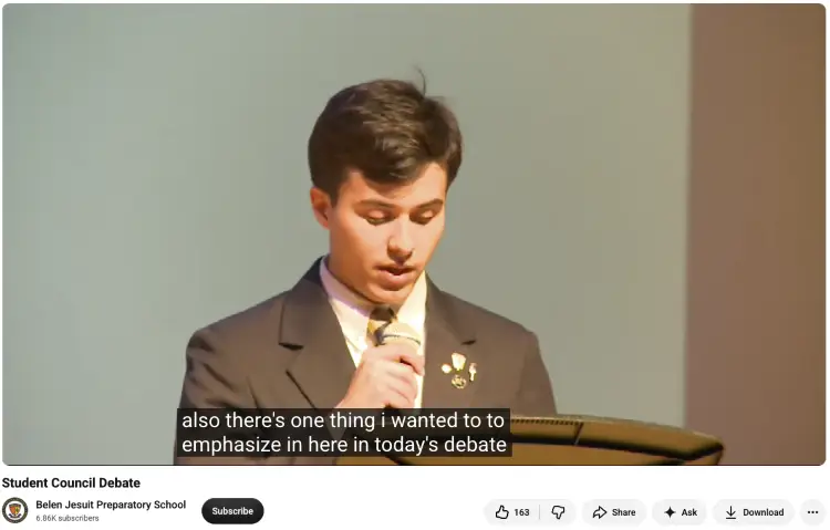 Student using a microphone to practice public speaking while presenting an argument during a school debate.