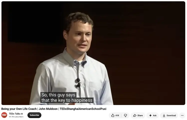 Speaker using a TEDx presentation to help the audience understand an idea about life coaching and happiness.